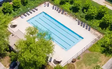 Aerial view of the Achasta lap pool and its deck with lounge chairs and umbrellas, framed by trees
